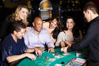 21_05_24 Five people at a casino table with an employee dealing cards _GettyImages-185118796