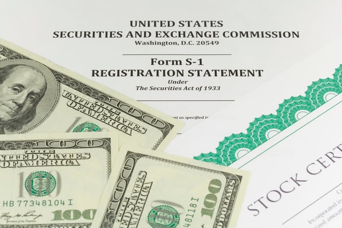 S-1 stock prospectus covered in a stock certificate and $100 bills.