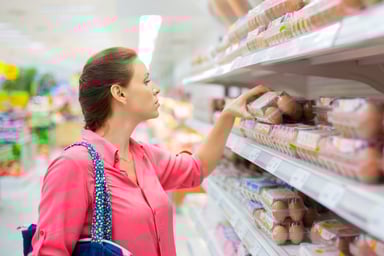 Shopper examines a carton of eggs in a grocery store.