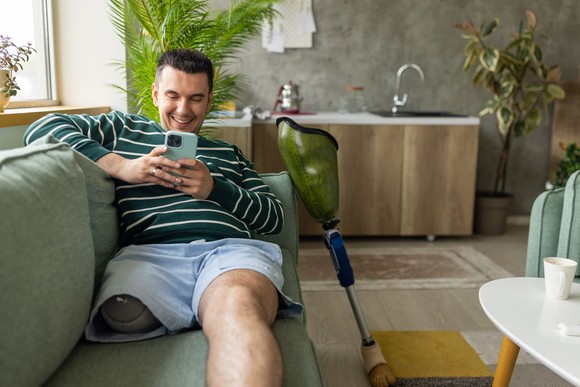 Someone on a couch is looking at a phone and smiling broadly.