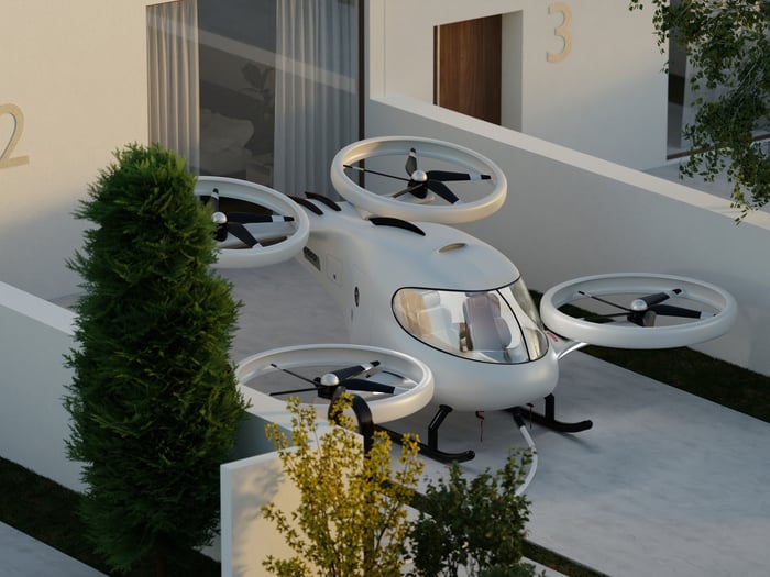 Rendering of a vertical take-off and landing vehicle parked in front of a residential building. 