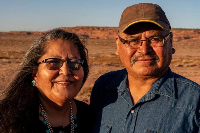 Two people standing outside in a desert, with slight smiles.