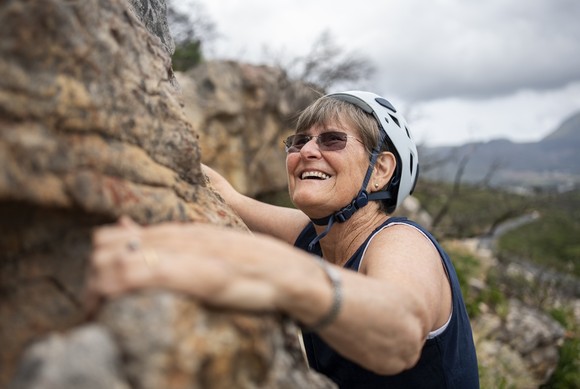 Someone is rock-climbing and smiling.
