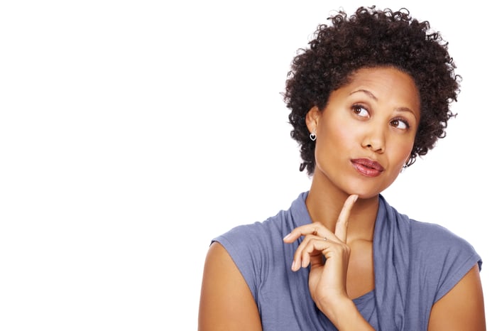 A person looks up thoughtfully, a finger on their chin.