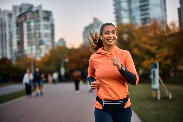 A person smiling while going for a run with headphones.