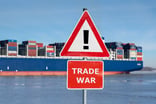 a trade war warning sign with a cargo ship in the background