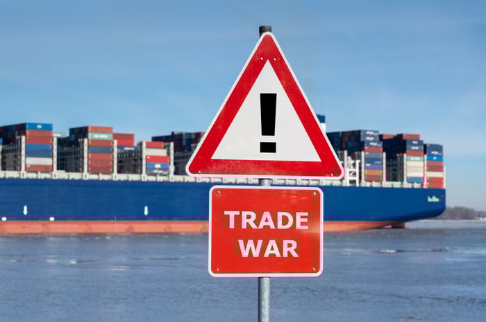 A "trade war" warning sign with a cargo ship in the background.