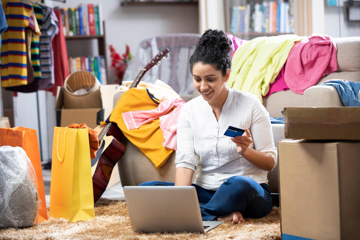 Person with credit card at computer surrounded by packages