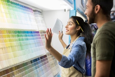 Two people smile while looking at a wall of color palettes.