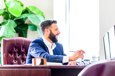 investor smiles while sitting at desk and looking at computer
