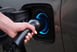 Hand holding a charger plugged into an electric vehicle
