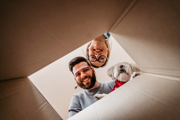 Two people looking into a box with their dog.