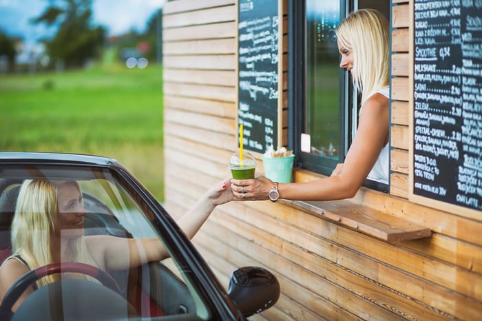 A person picking up their drinks at the drive-thru window.