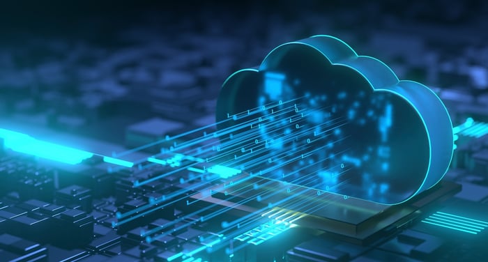 Rendering of a cloud computing concept featuring binary code coming out of a cloud over an abstract circuit board.