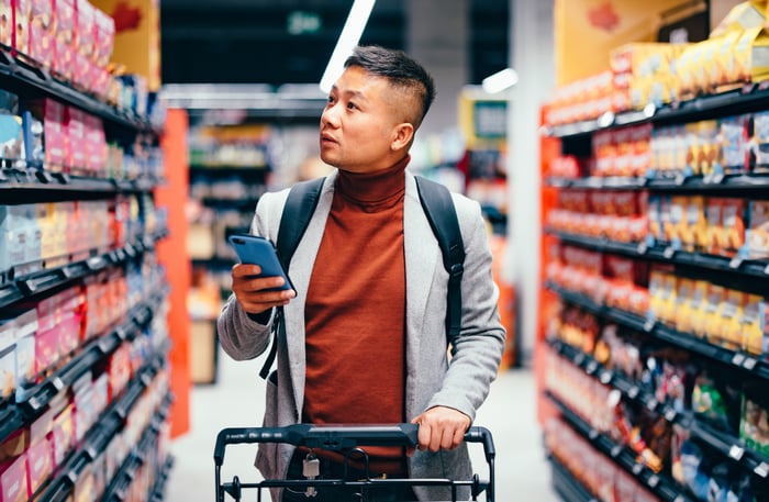 A customer using a mobile phone while shopping in a store.