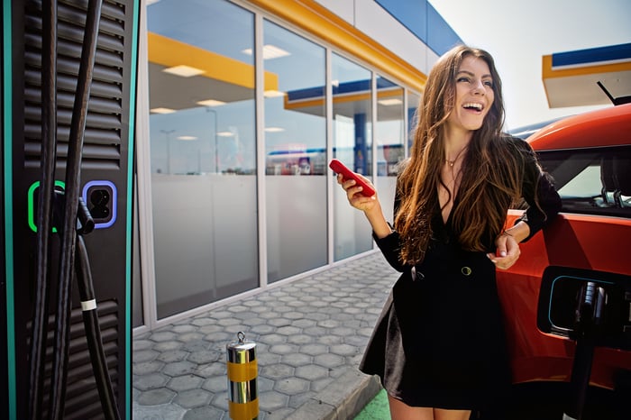 A person leans on an electric car.