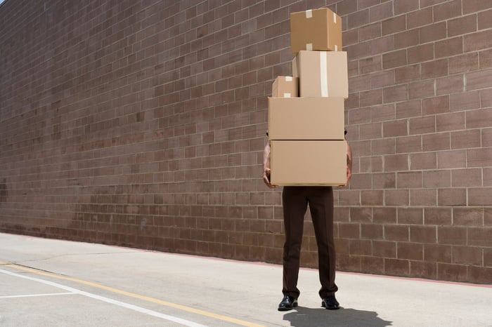 A delivery person holding a large pile of boxes that obscures their face.