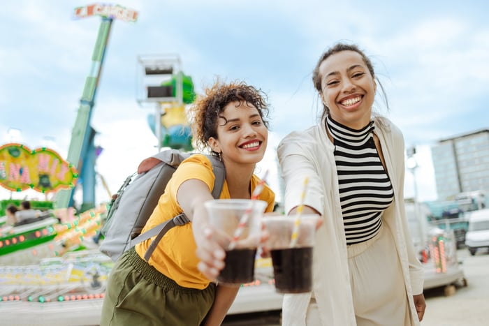Two people holding glasses of soda.