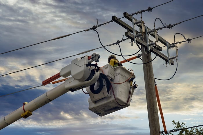 A person wearing personal protective equipment working on a power line.