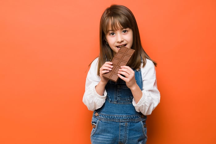 A child eating a large bar of chocolate.