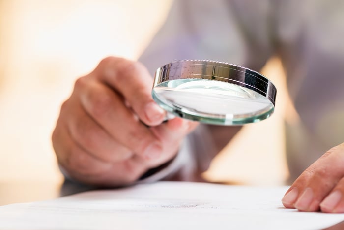 Person examines something with magnifying glass.