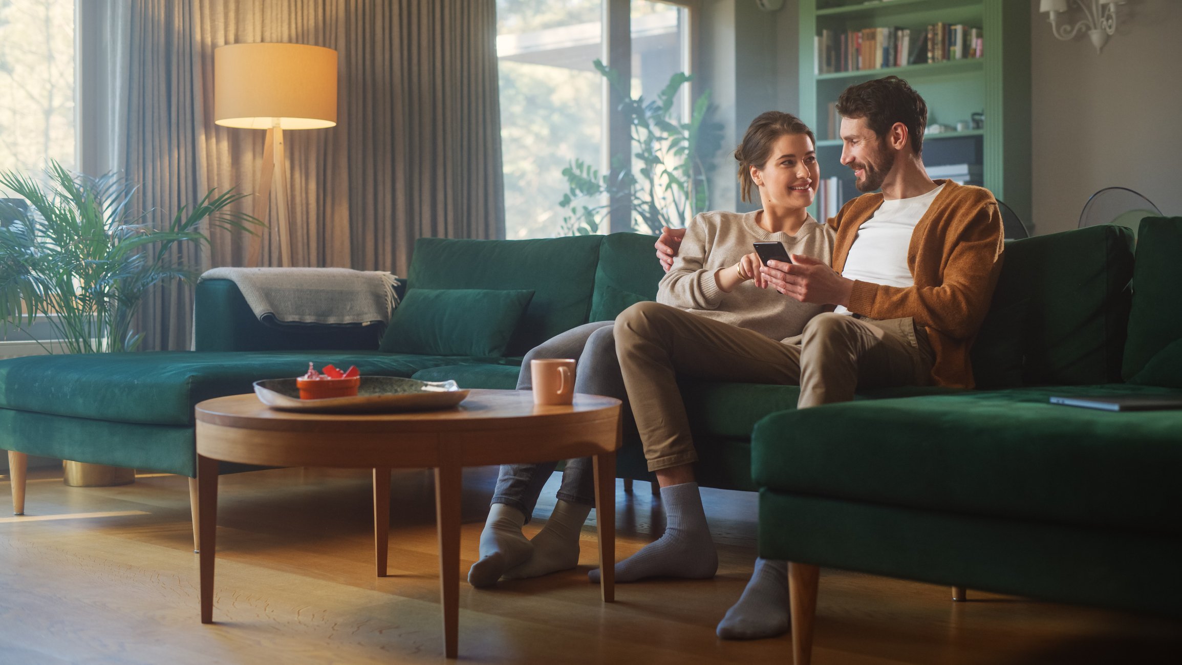 A couple on a couch having a discussion and consulting a smartphone
