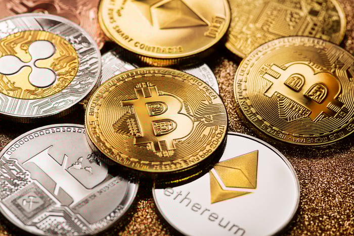 Several gold and silver coins with various cryptocurrency logos, including a Polkadot coin in the corner.