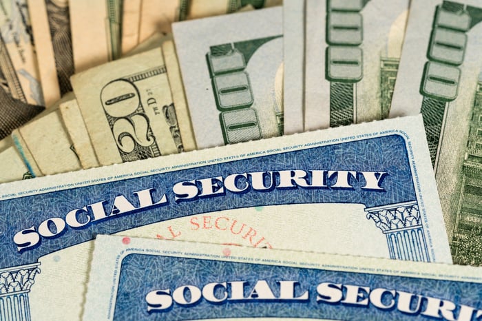 Two Social Security cards lay atop U.S. currency.