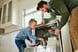 An adult and child work together to unload a dishwasher.