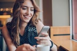 Person holding a smartphone and a mug.