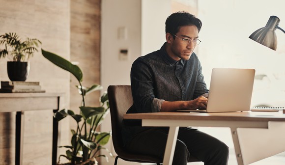 Serious person staring at laptop in office.