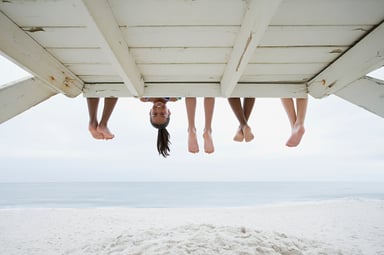 People's legs sticking out from under a boardwalk with one face