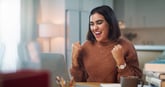 happy person at laptop success winning fists up victory yes