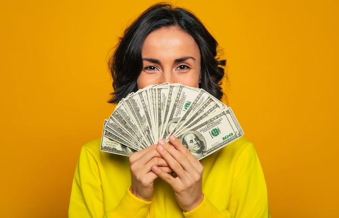 A person holding a fan of $100 bills.