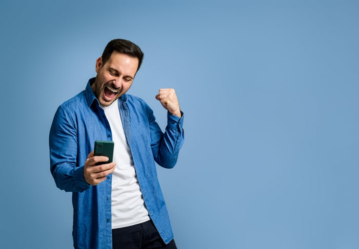 Investor doing a fist pump while looking at smartphone.