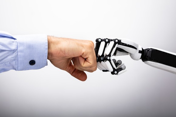 A human hand fist bumping a robot hand.