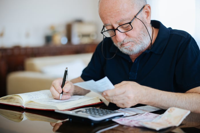 A person writing in a notepad while looking at a piece of paper.