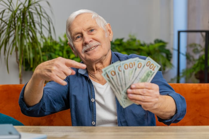 Person holding a handful of $100 bills.
