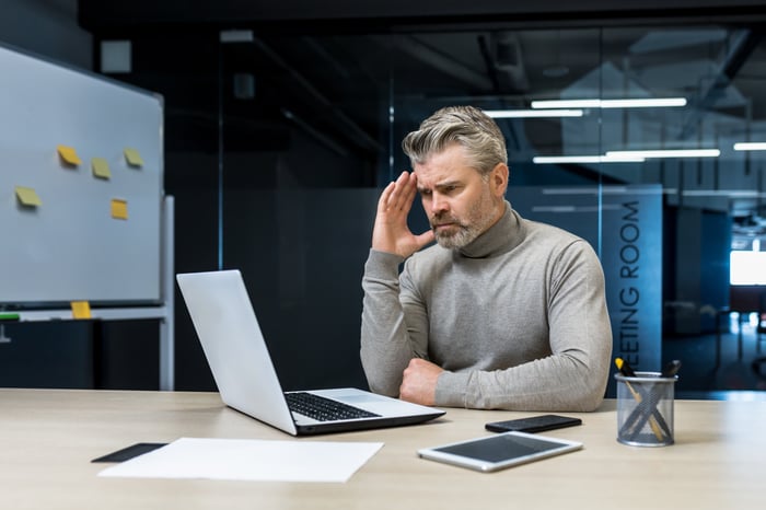 A person looking at their laptop confused.