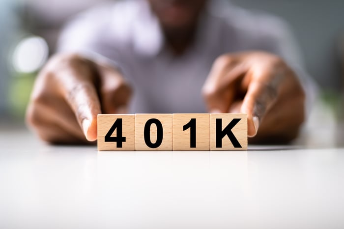 Fingers next to wooden blocks spelling "401K."