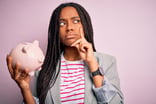 23_11_08 A person holding a piggy bank with a thinking or questioning expression on their face _MF Dload -1201x800-5b2df79