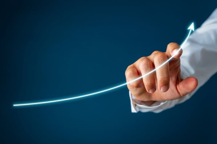 A person pointing on the line of an upward sloping chart.