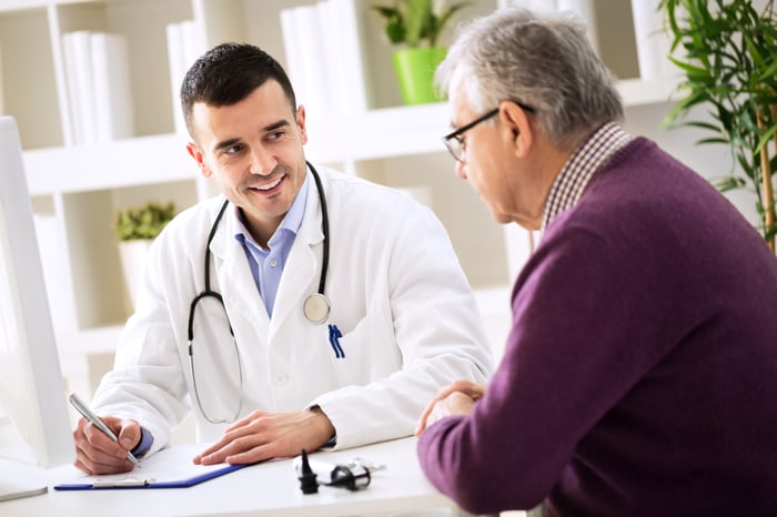 Doctor talking to a patient while making notes.