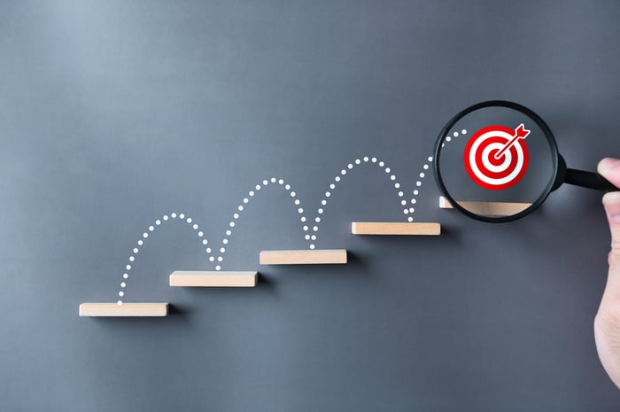 A bullseye jumping up stairs with a magnifying glass on it.