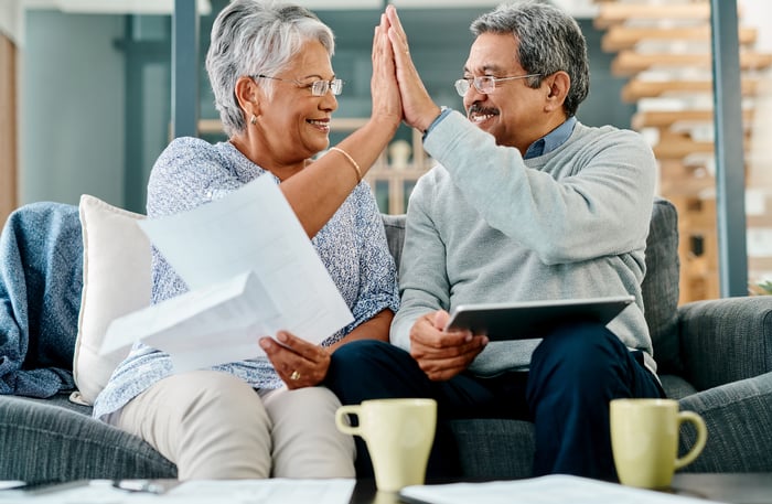 Two people sitting on a couch and high-fiving.