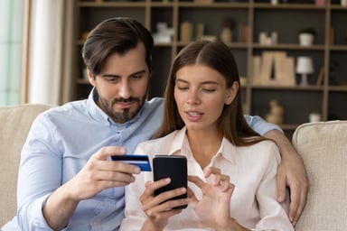 A young couple keying credit card information into a smartphone screen