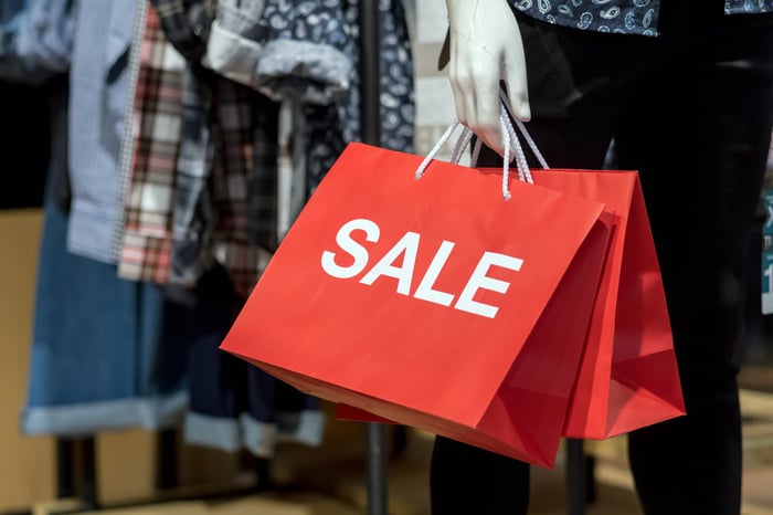 A mannequin holding a bag that says sale.