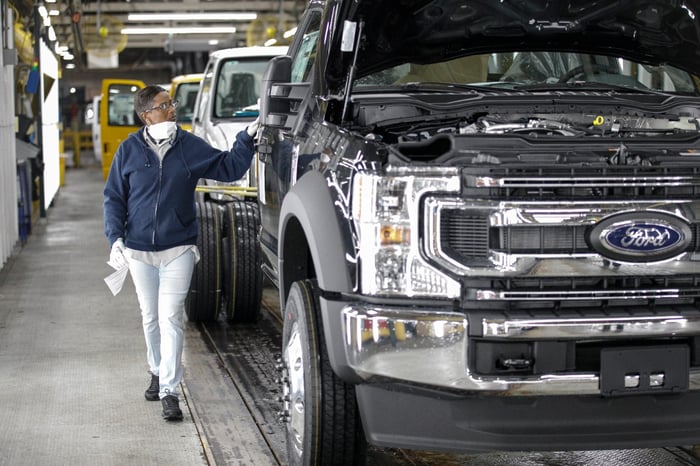 Person inspecting a Ford truck on an assembly line.