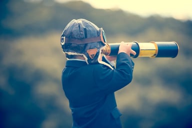 child wearing leath aviation cap looks in telescope.