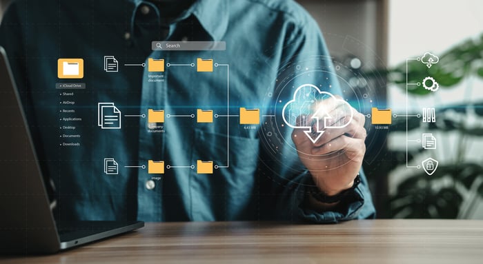 Person facing folder icons on a transparent screen with a cloud image in one quadrant.